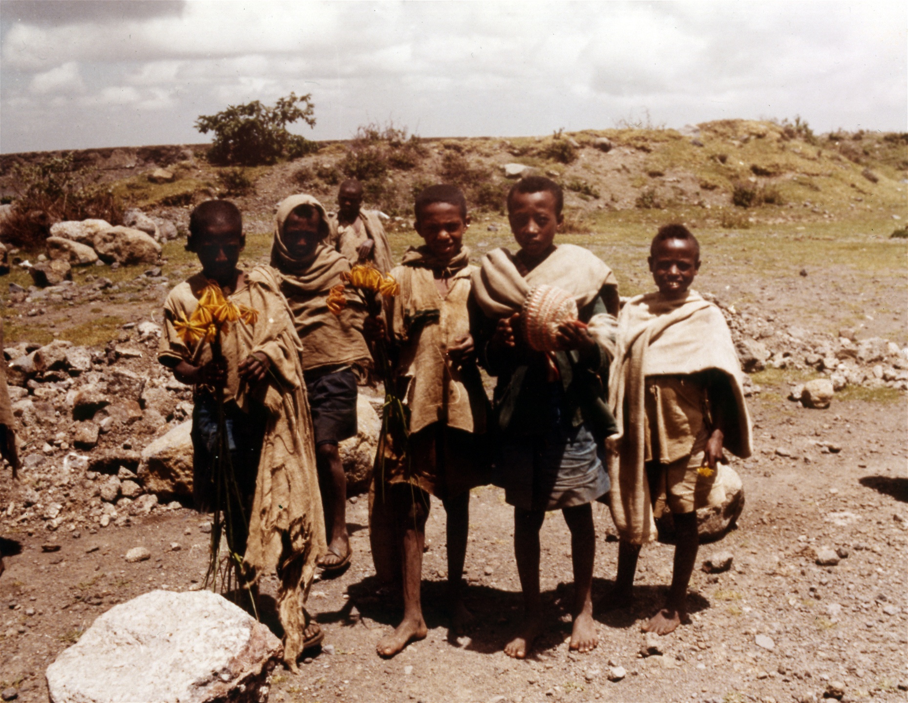 Bilden från 1974 visar barn från Bana-stammen i norra Etiopien som säljer souvenirhattar och exotiska blommor till besökare i området.