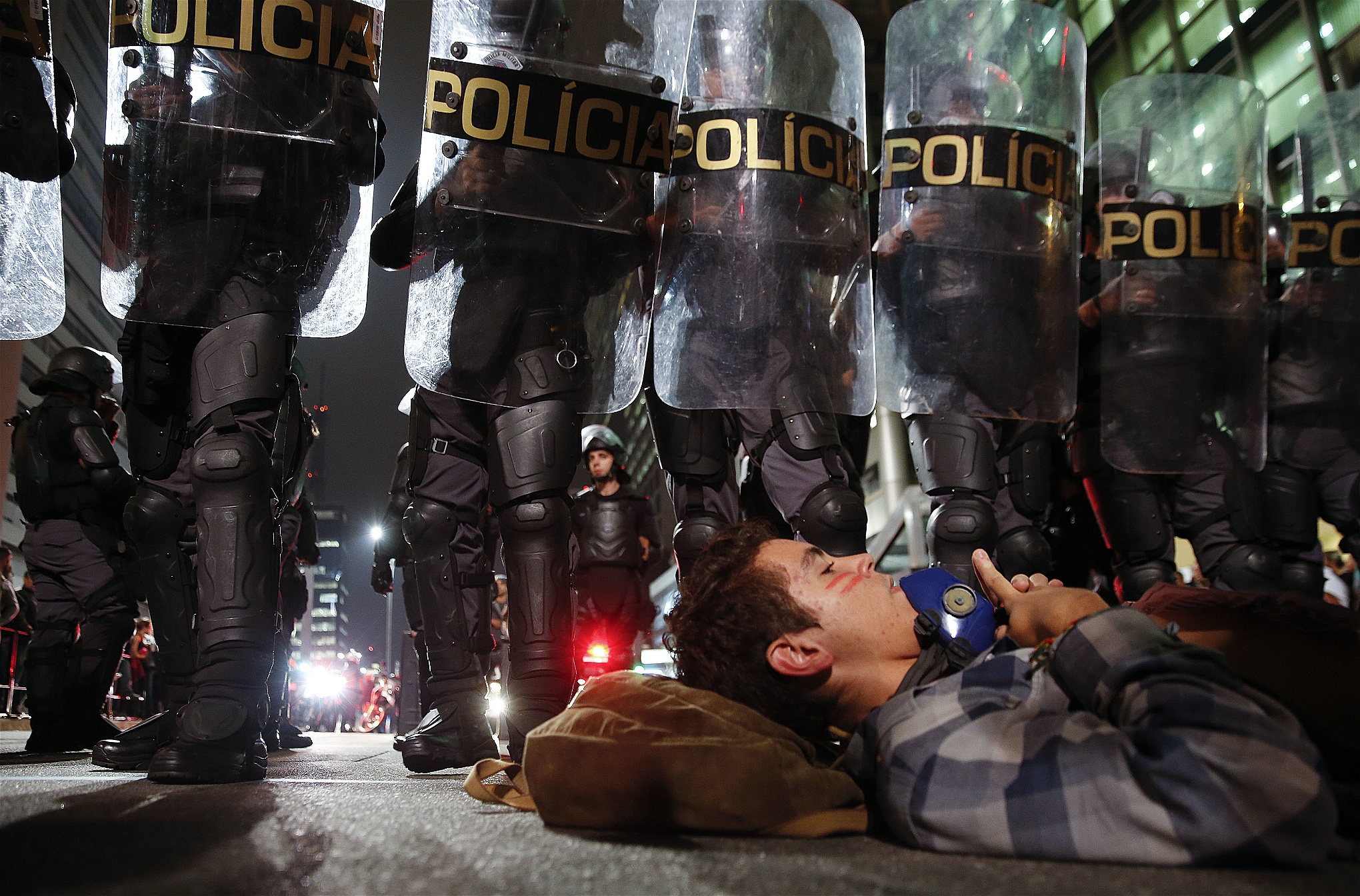En demonstrant ligger på marken intill en polisbarrikad vid en protest i Sao Paulo den 1 juni mot gängvåldtäkten av den 16-åriga flickan.