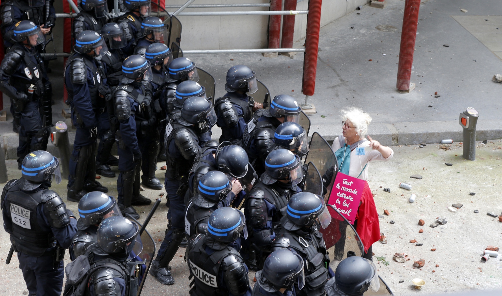 En kvinna argumenterar med kravallpolisen i Paris. På hennes väska står det 