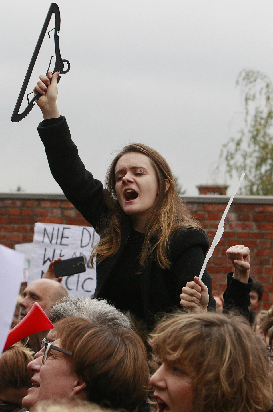 En polsk kvinna skriker slagord hållandes i en galge, symbolen för illegala aborter, vid demonstrationen i Warszawa i måndags.