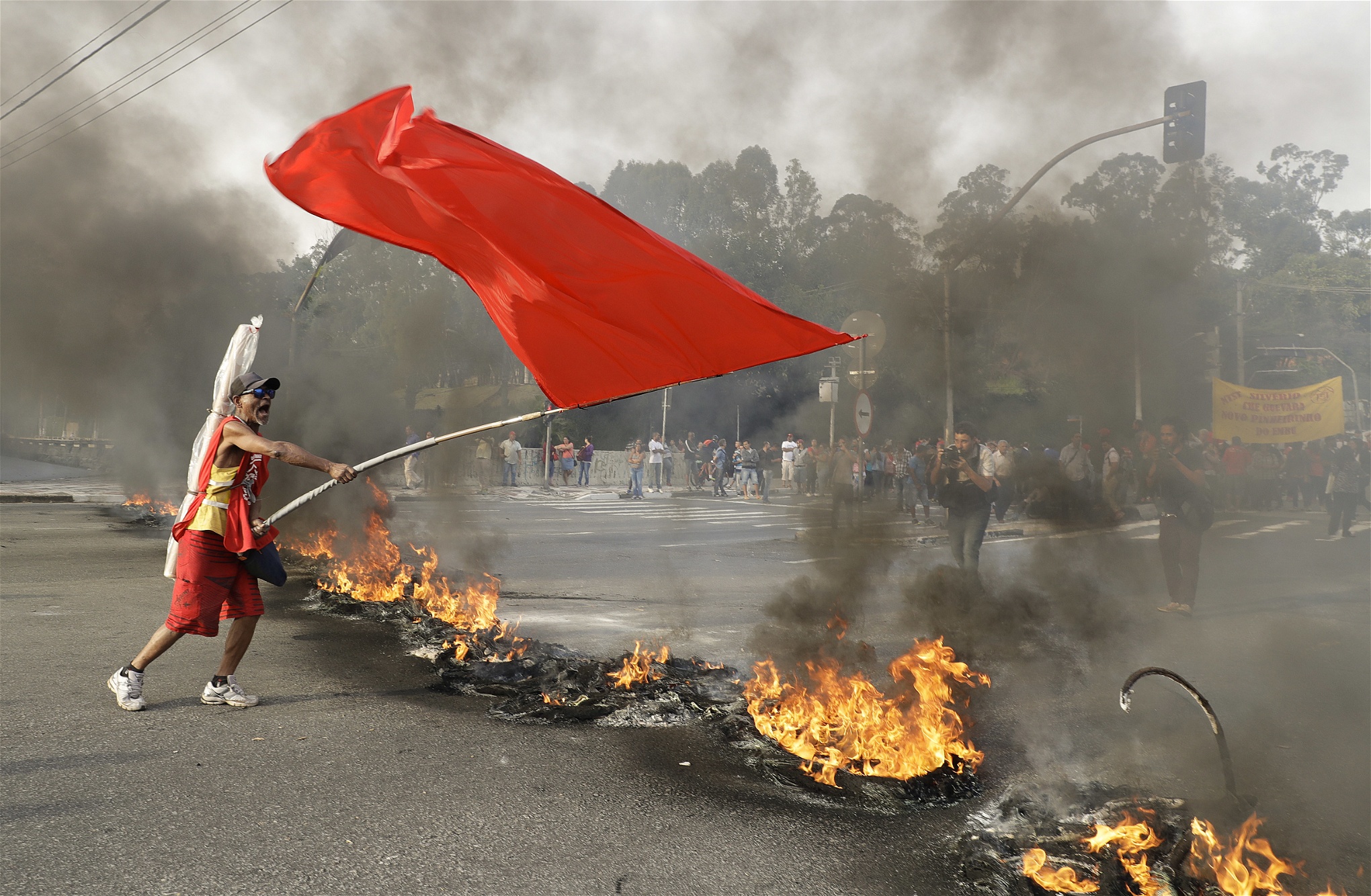En demonstrant viftar med en röd flagga  vid en brinnande barrikad under en protest mot Brasiliens tillfälligt tillsatte president Michel Temer i Sao Paulo den 30 augusti. 