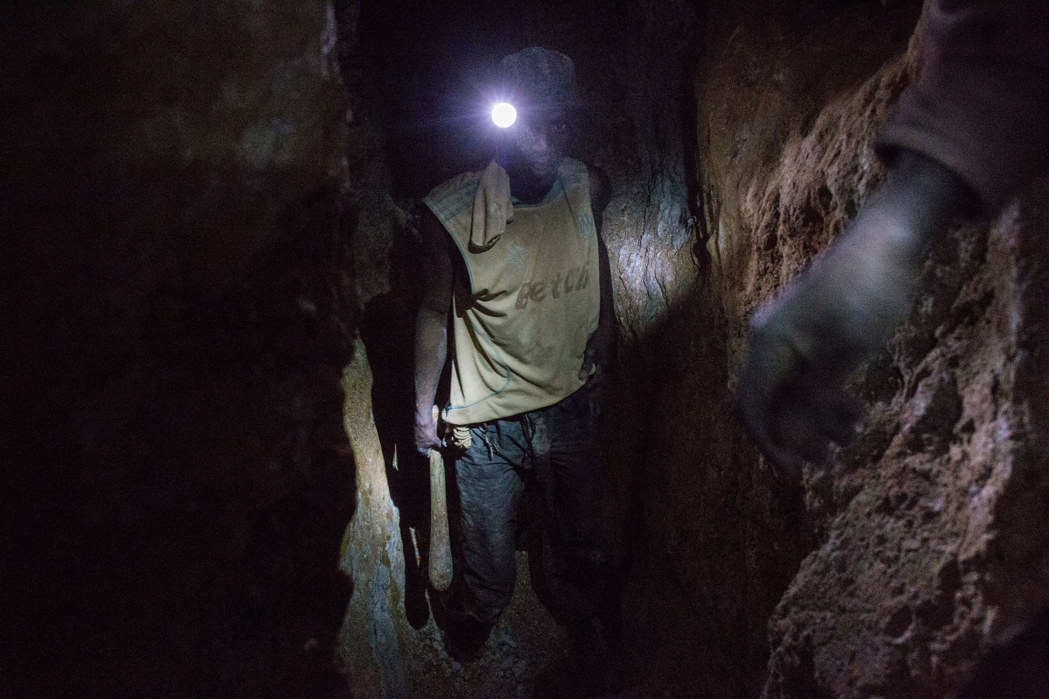 En ung gruvarbetare rör sig mellan två schakt. I delar av gruvan råder stor fallrisk.
