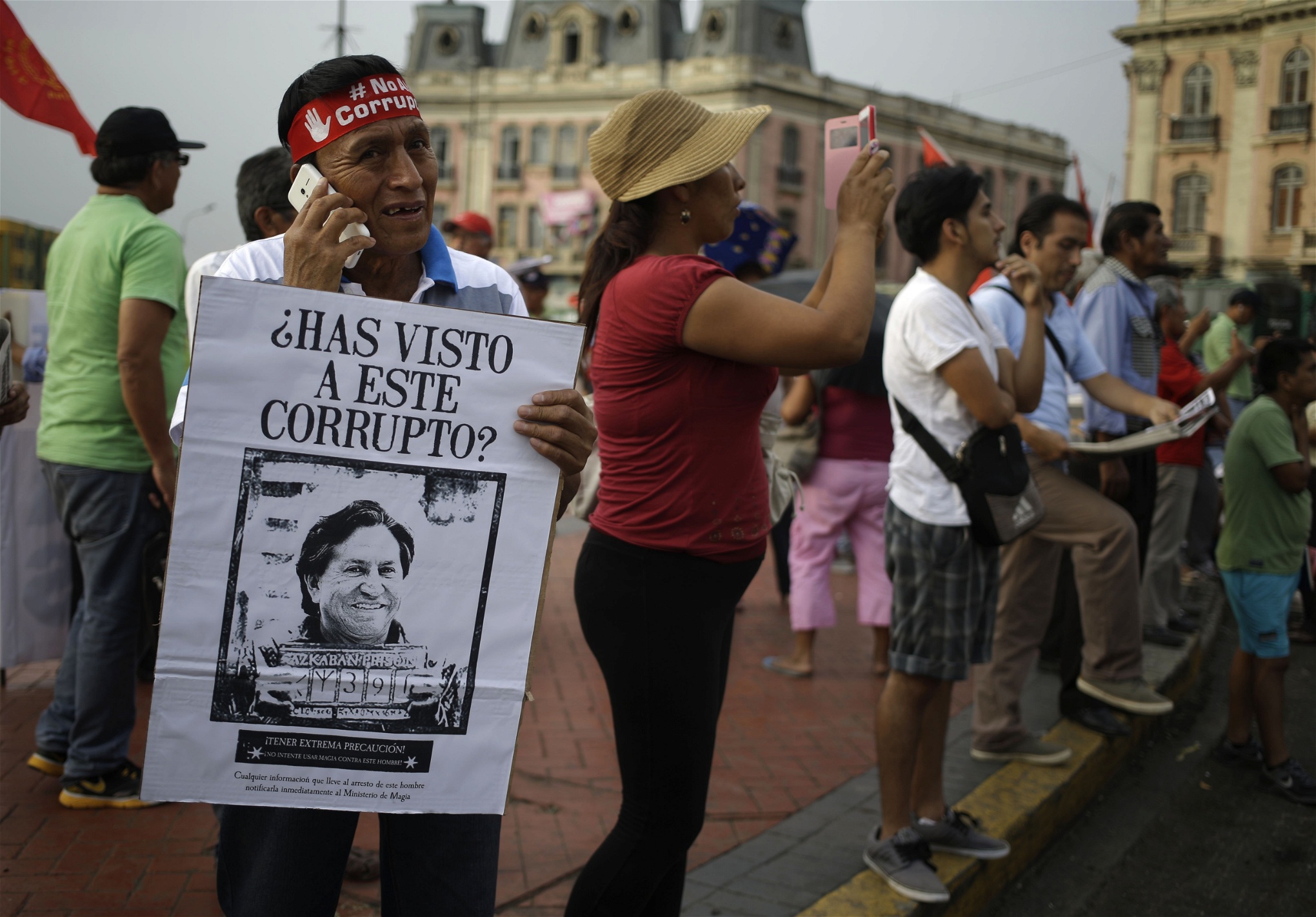 En man håller upp ett plakat med texten ”Har ni sett den här skurken?” och en bild på Perus förre president Alejandro Toledo vid en demonstration i Perus huvudstad Lima. Toledo är efterlyst för inblandning i korruptionshärvan.