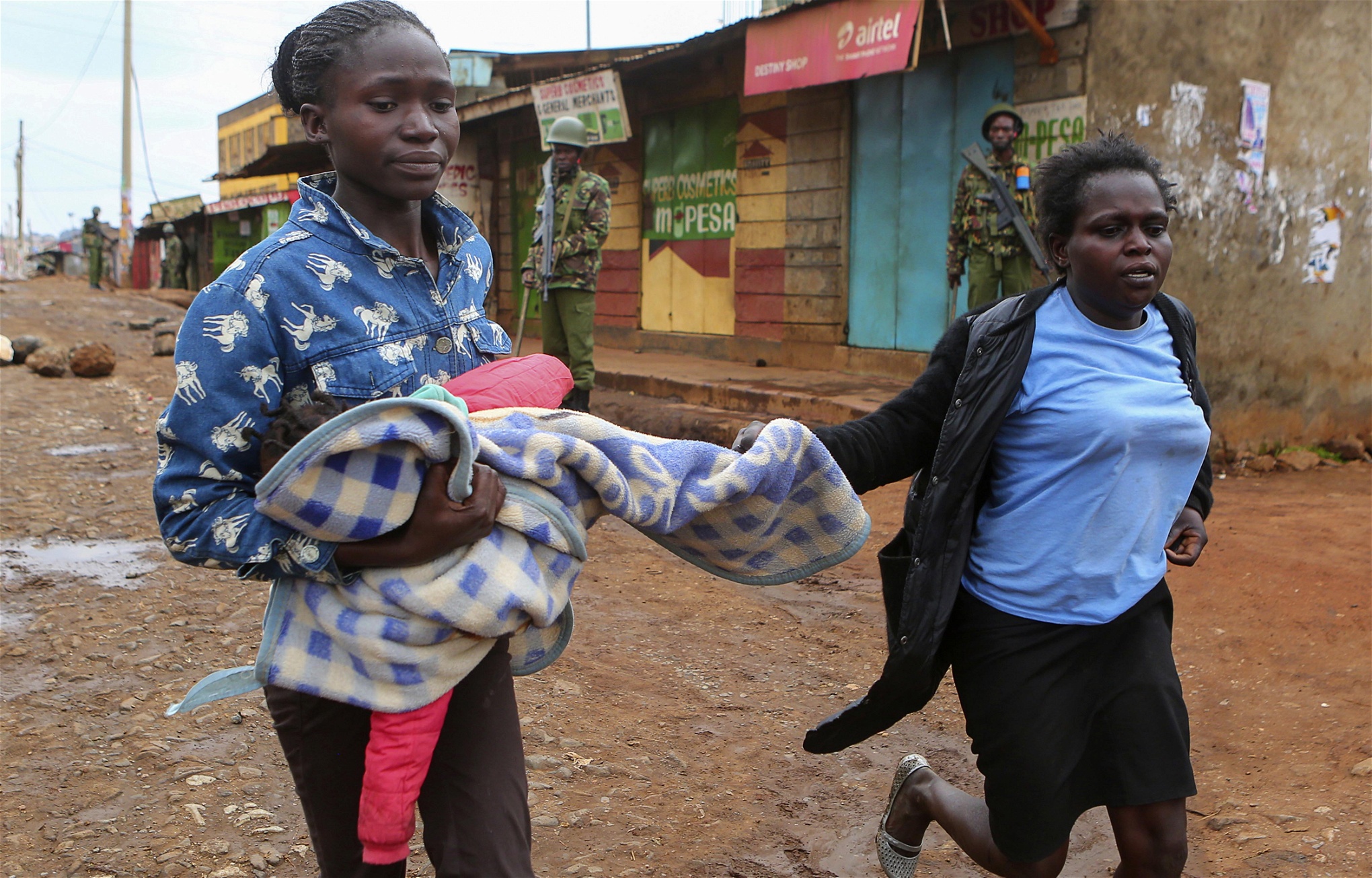 Två kvinnor i Kawangware, en av dem bärande ett barn, försöker sätta sig i säkerhet.