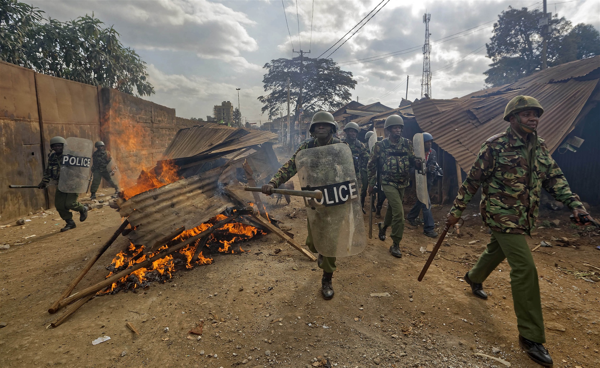 Kravallpolis springer förbi brinnande barrikader som rests av protesterande invånare i Kawangware i huvudstaden Nairobi.