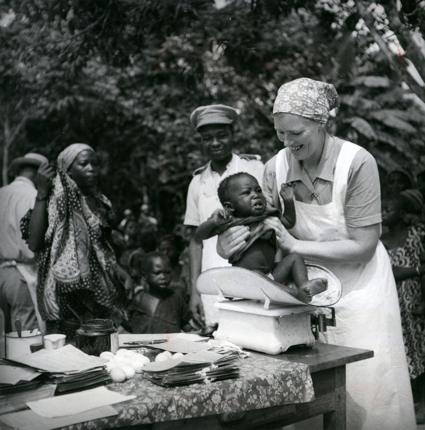 Agnes Svensson, missionär i Belgiska Kongo, väger ett spädbarn under ett besök i en by, några decennier efter de tidiga missio­nä­rernas ankomst. Som missionärerna hoppats innebar kolonia­lstatens tillkomst att den förkoloniala politiska organisa­tionen kringskars. 