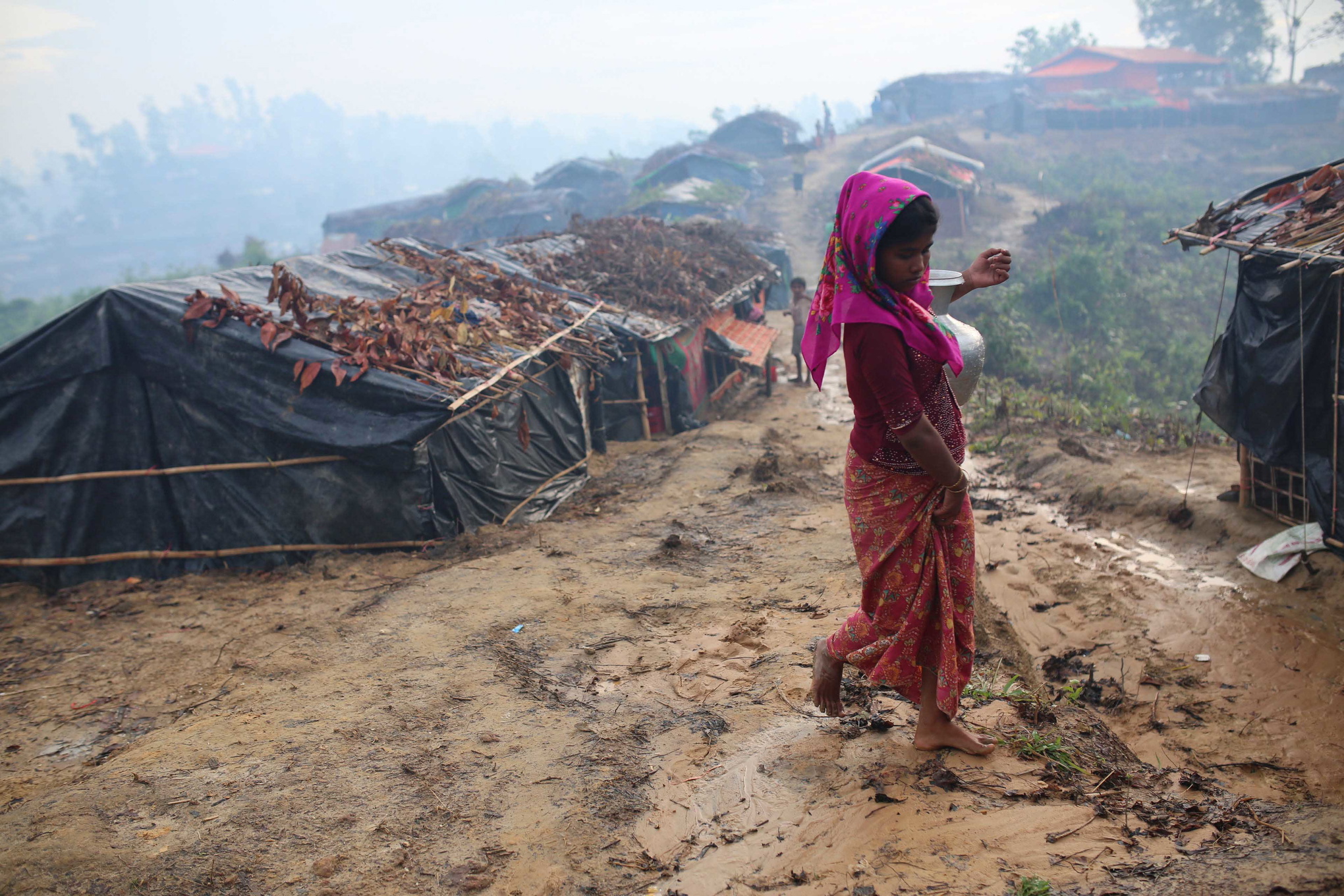 En rohingyaflicka går för att hämta vatten på de leriga stigarna genom ett av flyktinglägren i Cox's Bazar. Över en halv miljon rohingyer har flytt från Burma till Bangladesh de senaste månaderna.