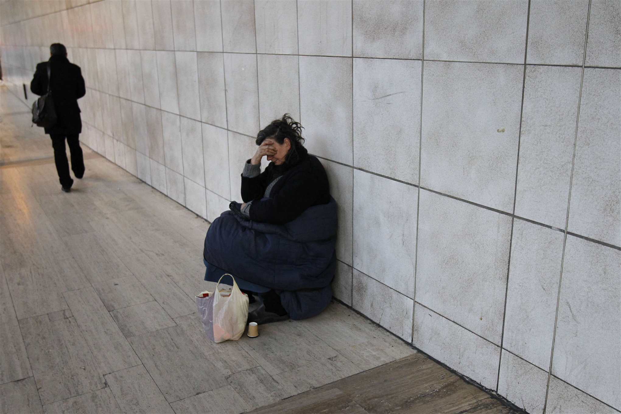 En hemlös kvinna tigger vid Montparnasses metrostation i Paris.