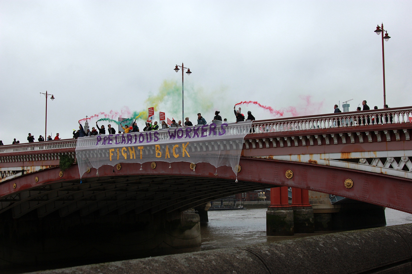 Demonstranterna hissar ned en banderoll vid  Blackfriarsbron. Fackförbundet IWGB beskriver manifestationen som ”den största prekära demonstrationen i landet någonsin”. 