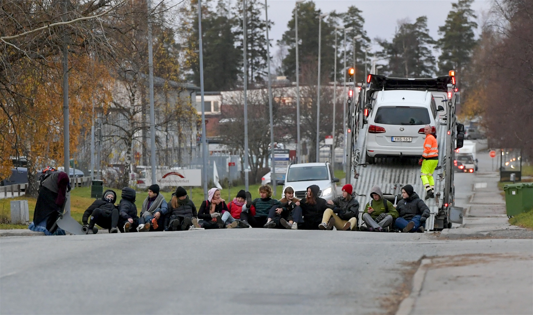 Aktivister sitter på gatan för att blockera utfarten från Migrationsverkets lokaler i Märsta för att försöka stoppa en väntad utvisning.