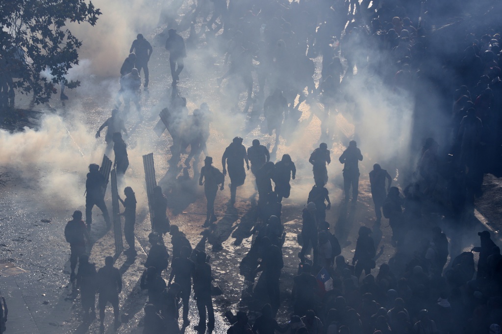 Demonstranter i tårgashav, Santiago den 21 oktober. ”Etablerade medier i Chile och i världen sprider okritiskt militärens propaganda”, skriver Esteban Calderón.