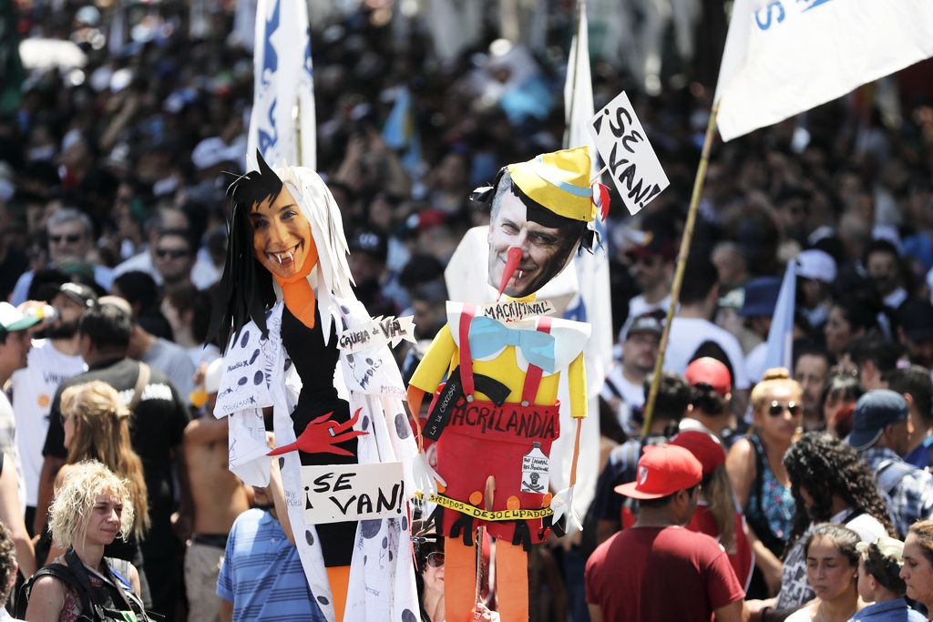 Supportrar av Argentinas nya president Alberto Fernández håller upp avbildningar av den avgående presidenten Mauricio Macri, till höger, och den avgående guvernören i delstaten Buenos Aires, Maria Eugenia Vidal, till vänster, under installationen av den nya presidenten i december 2019.