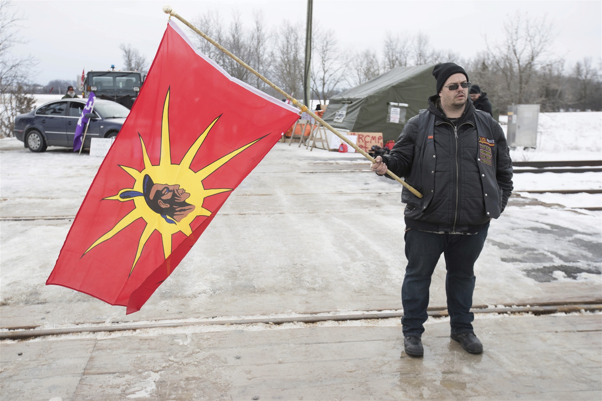 En man med en krigarflagga, vid järnvägsblockaden i på Tyendinaga Mohawk-territorium, i början av februari, då blockaden pågått i en dryg vecka. 