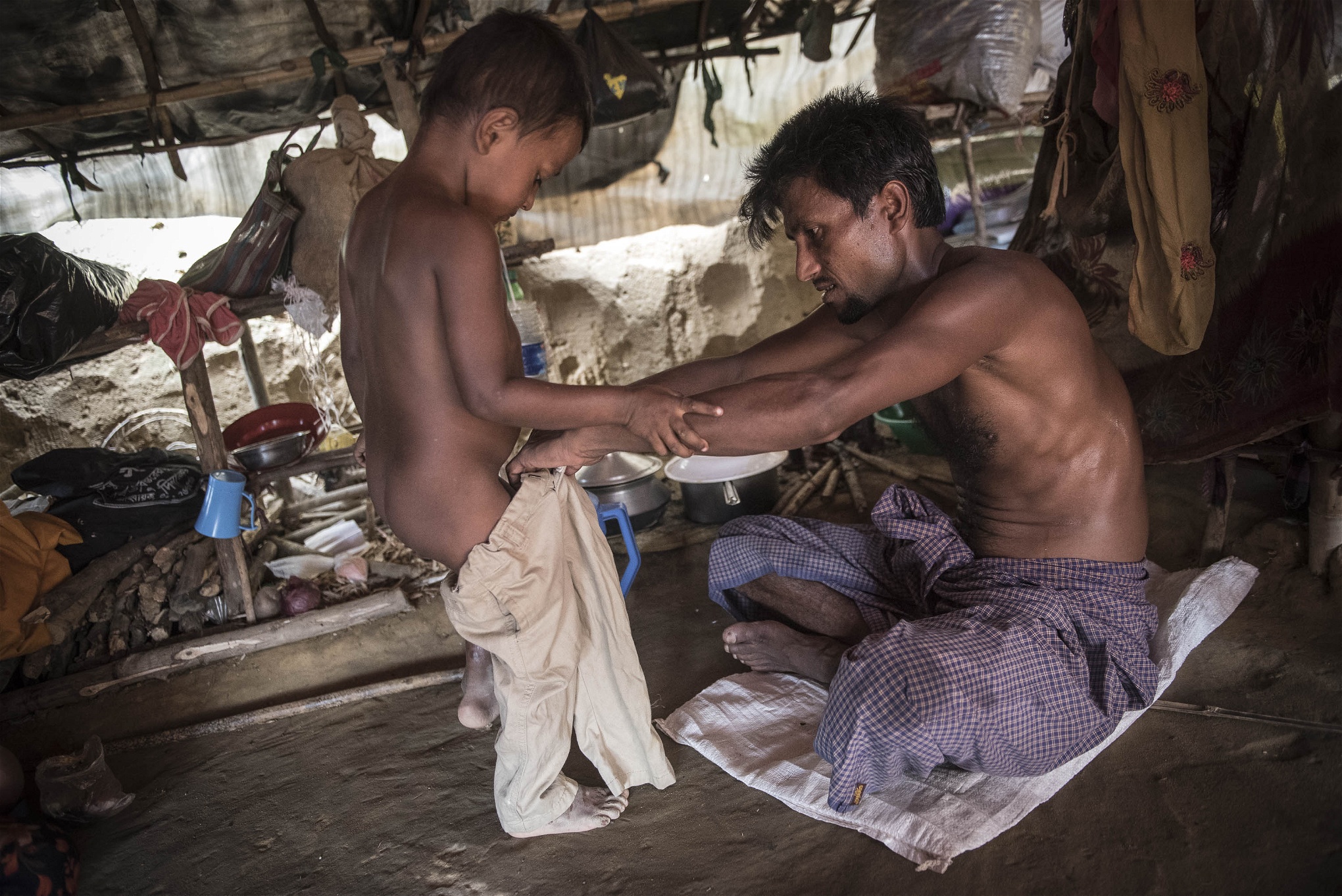 Annar Sadik, 4 år, får hjälp av sin pappa Roshid Ullah 27år att ta på sig byxorna. Ullah bar sin son hela vägen under flykten från Myanmar till Bangladesh. Foto: Troy Enekvist