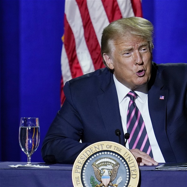 Donald Trump vid ett podium framför en amerikansk flagga, pekar med fingret och säger något.