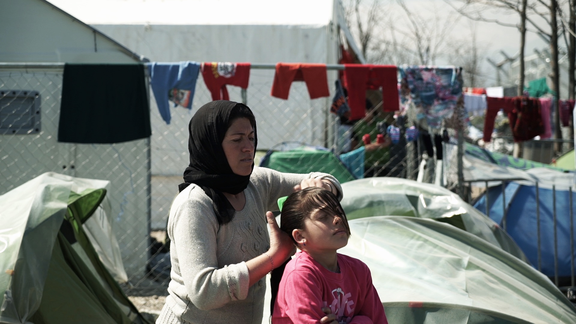 Mamma tvättar sitt barns hår i flyktinglägret Idomeni.