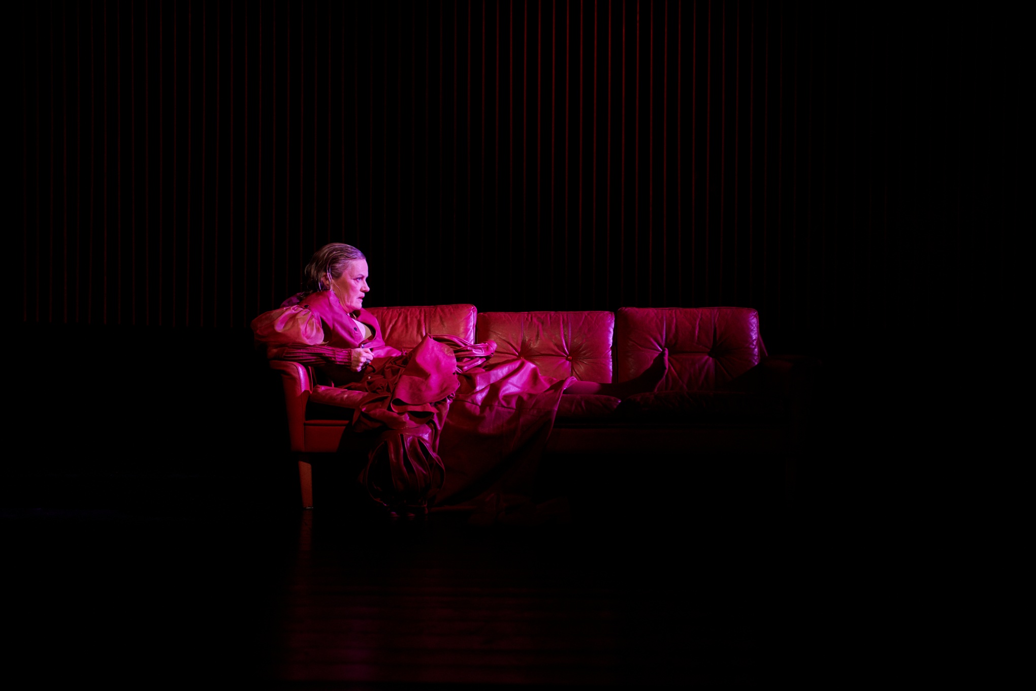 Thérèse Brunnander som Gustav Vasa sitter i en skinnklädd soffa och grubblar, i pjäsen Gustav Vasa.