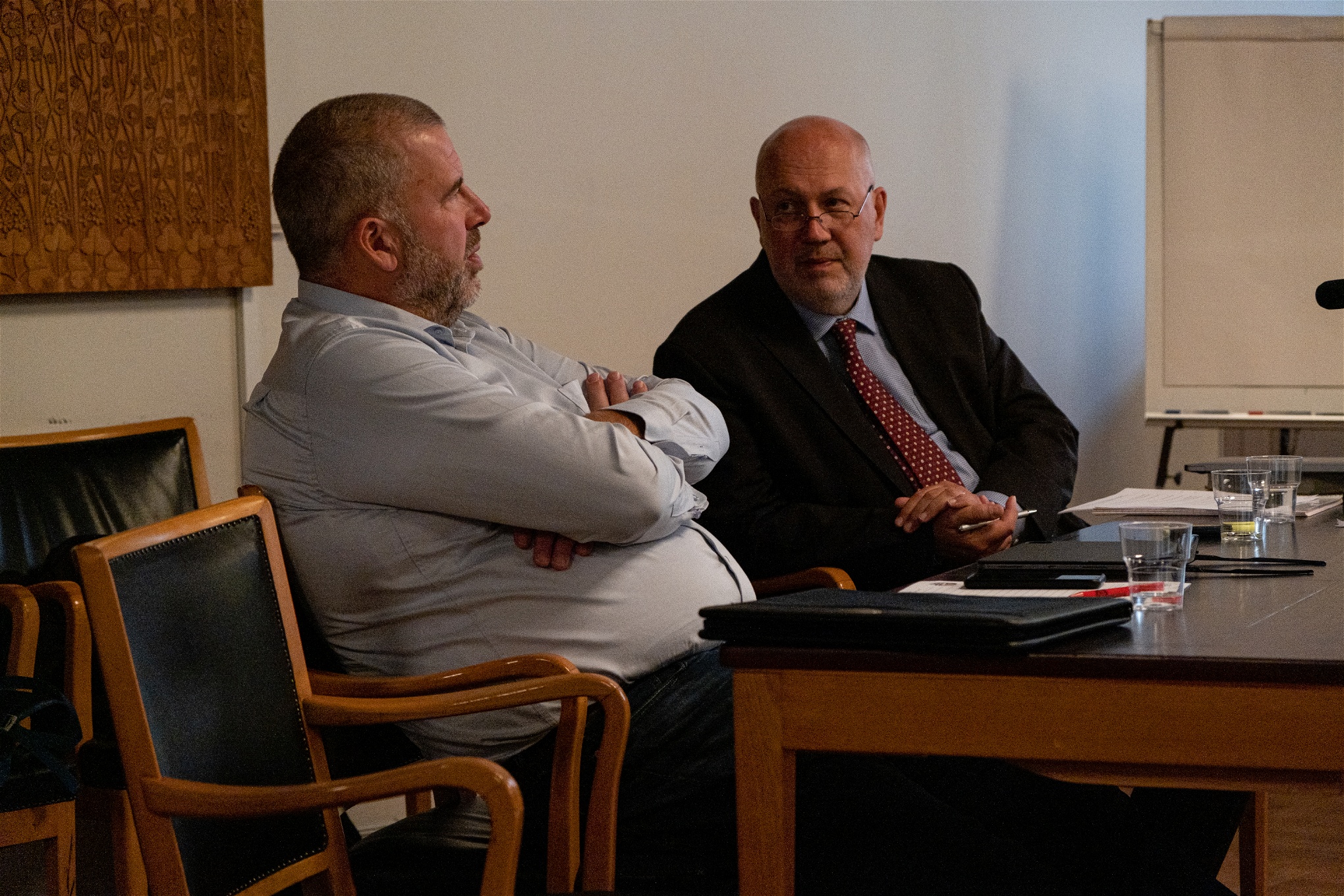 Martin Berg, ordförande i Hamnarbetareförbundet sitter tillbakalutad vid ett bord med händerna korsade över bröstet, i samspråk med Anders Karlsson, advokat som företräder förbundet.