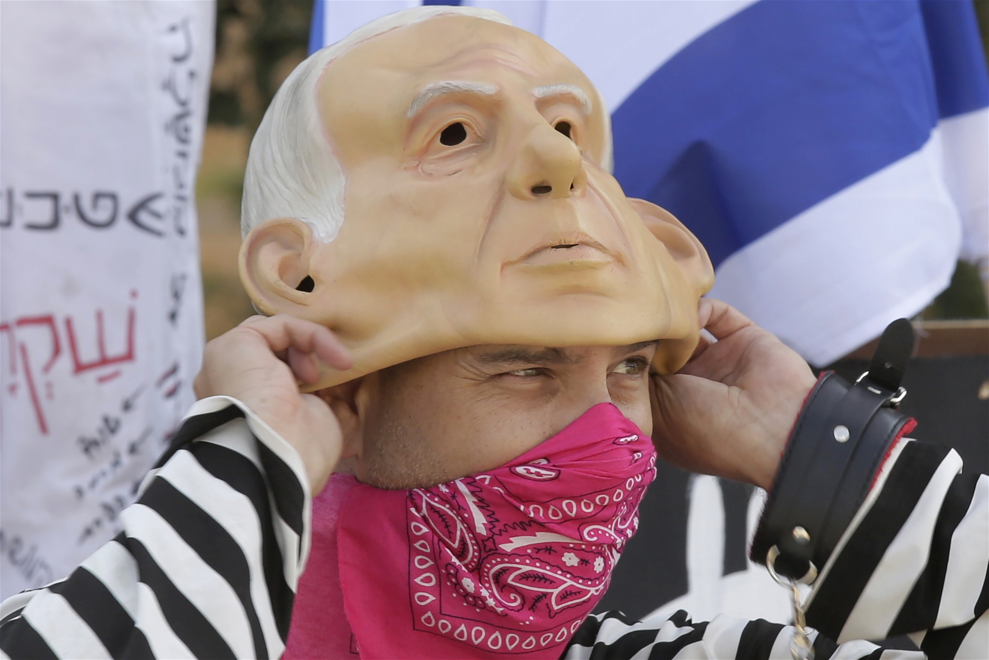 En demonstrant i Israel bär en gummimask föreställande premiärminister Benjamin Netanyahu.