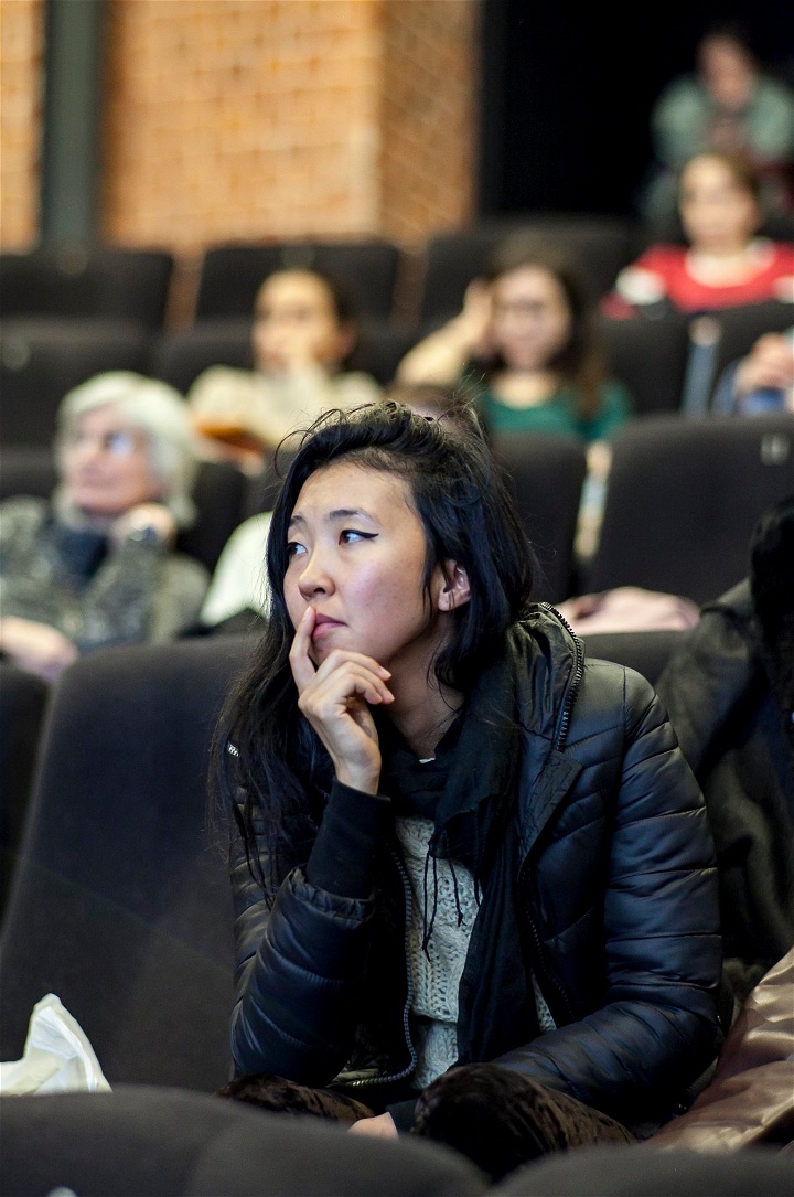 Den unga krigiziska statsvetaren Bermet Borubayeva i en föreläsningssal. Hon lutar hakan mot sin hand och ser ut att lyssna.