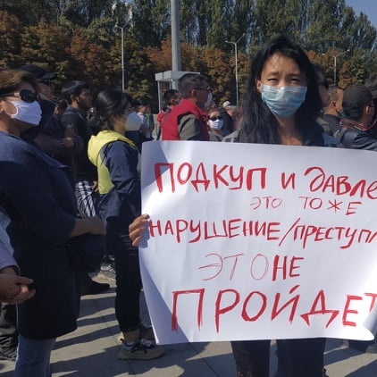 Statsvetaren Bermet Borubayeva med en protestskylt under en demonstration.
