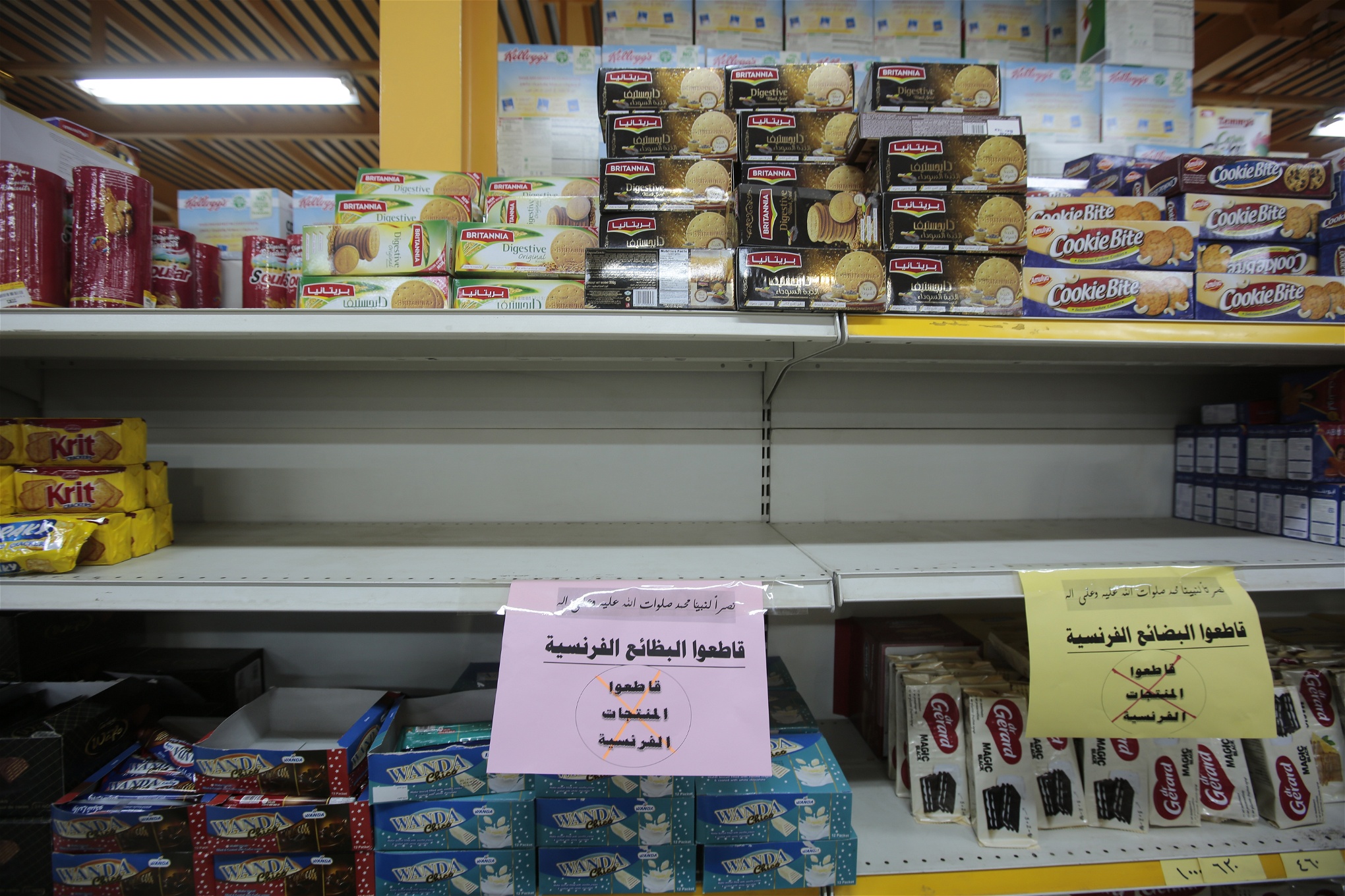 En butikshylla som gapar tom, skyltar med arabisk text uppmanar till boycott av franska varor.