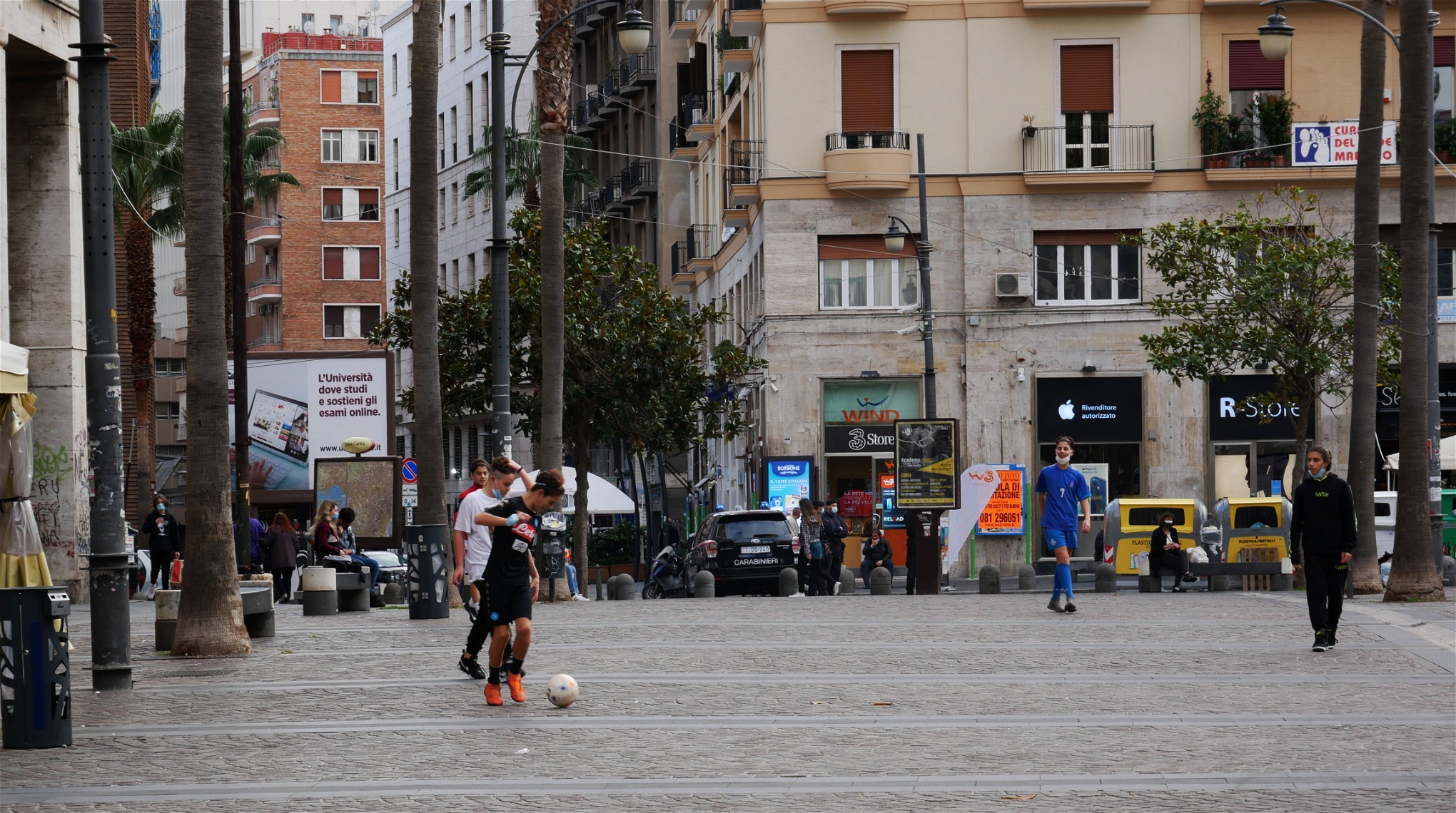 Foto: Giuliano EspositoUngdomar spelar fotboll på Piazza Carita. Det är obligatoriskt för alla att bära munskydd utomhus.