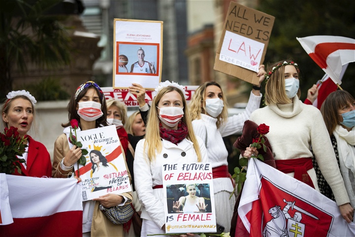 Kvinnor med vita kläder, håller rödvita flaggor, rosor och plakat där det bland annat står The future of Belarus is female.