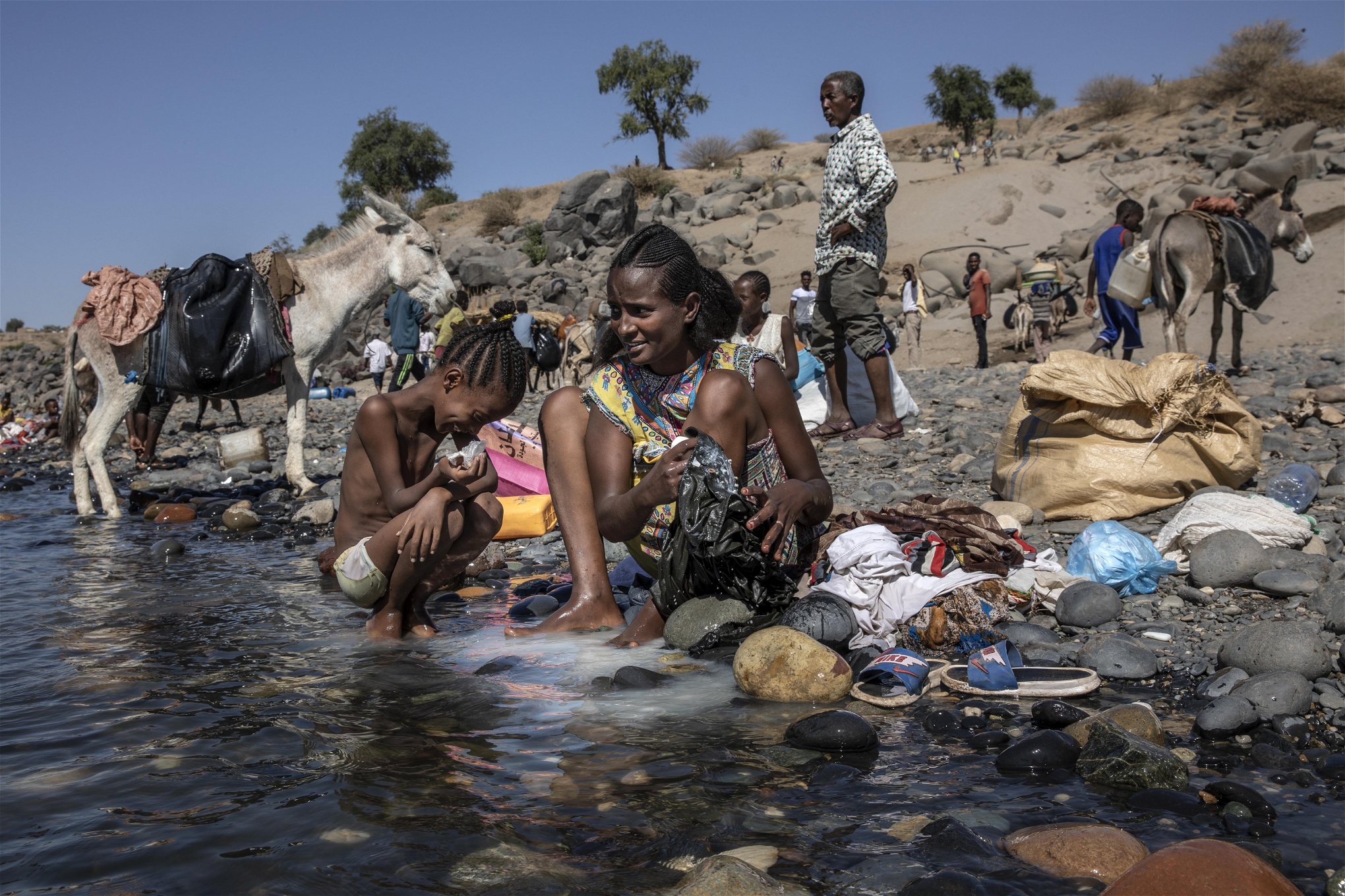 Tigreanska flyktingar som flytt över gränsen till Sudan tvättar kläder i Tekezefloden på den sudanesiska sidan av gränsen. Foto: Nariman El-Mofty/AP/TT