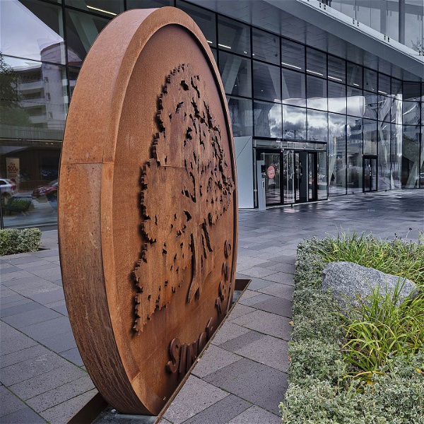 Entrén till Swedbanks huvudkontor i Sundbyberg. En skulptur av bankens logotyp, lite växtlighet och en glasfasad.