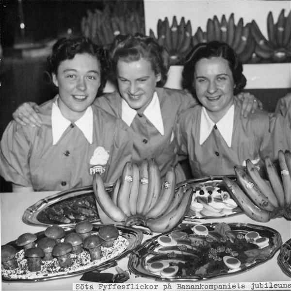 Tre kvinnor med mat och frukt framrör sig på en historisk bild.
