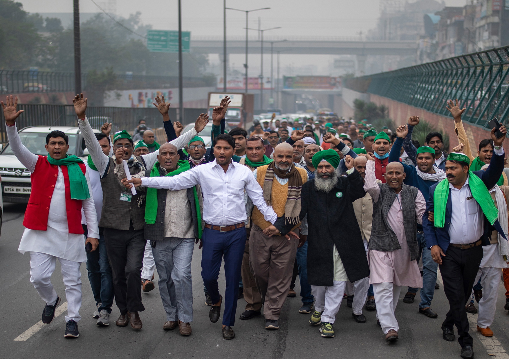 Indiska bönder med gröna hattar och halsdukar blockerar en motorvägsfil i Delhi.