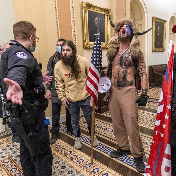 Fyra Trumpsupportrar utanför senatskammaren, inne i Kapitoleum. En av dem har buffelhorn på huvudet, päls över axlarna och många tatueringar.