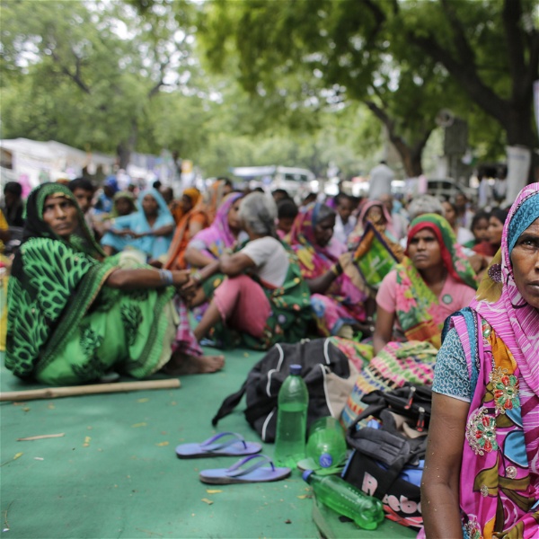 Kvinnliga bönder i färgglada saris sitter på marken i en av den senaste tidens många bondeprotester i Indien.