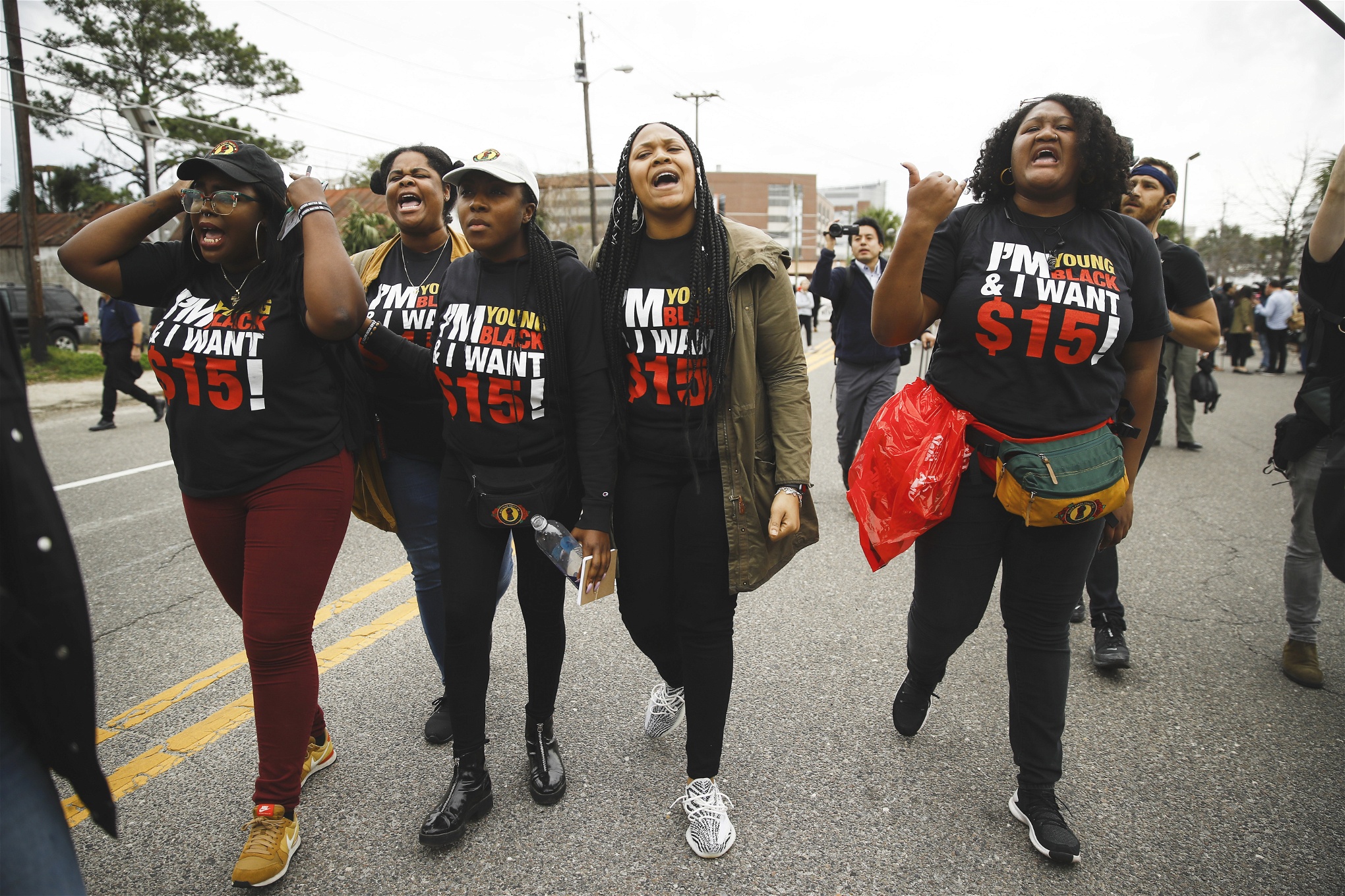 Fyra afroamerikanska kvinnor i ett demonstrationståg. På deras svarta t-shirts står det Fight for 15 med vitt och rött.