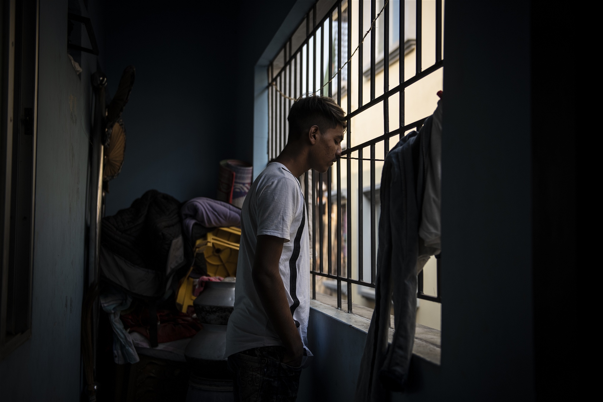 Md Sohel Sheik, 14, kollar ut genom gallret på den balkong han sover på tillsammans med sin äldre bror. Rummet deras familj delar är för litet för att de ska få plats att sova inomhus. Foto: Troy Enekvist