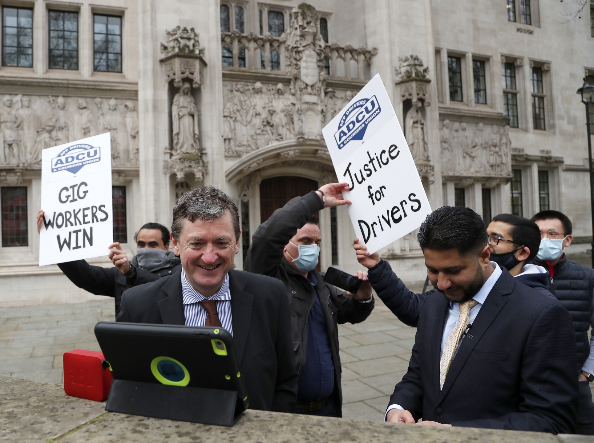 Foto: Frank Augstein/TTFörare i facket ADCU (App Drivers & Couriers Union) i Storbritannien firar det rättsliga beslutet att förare ska numera ska betraktas som anställda. Bilden är tagen utanför högsta domstolen i London den 19 februari 2021.
