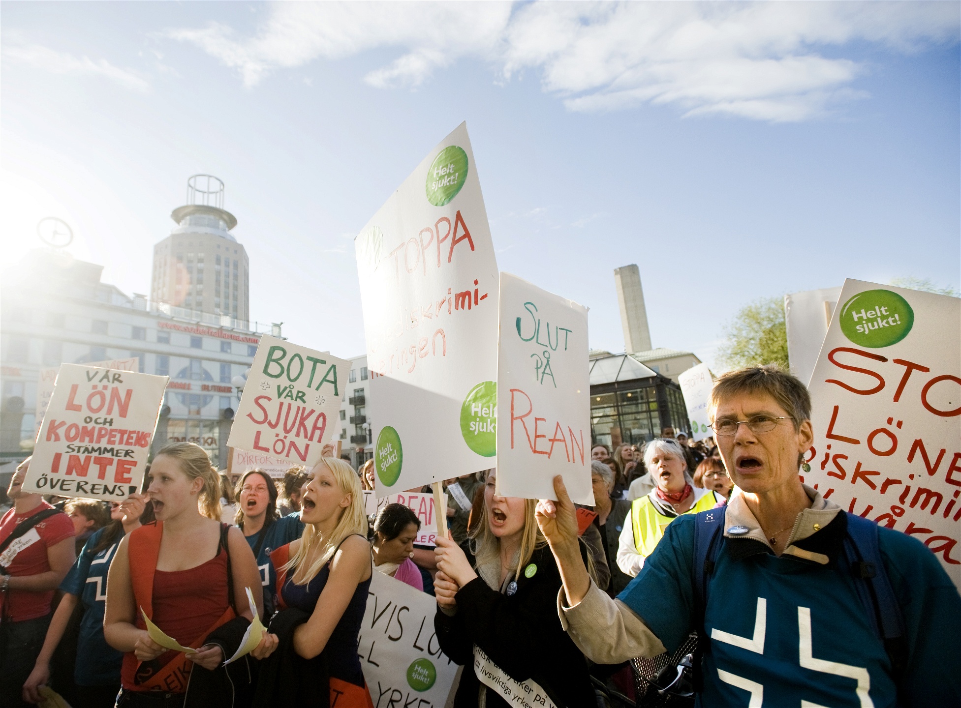 Medlemmar i Vårdförbundet demonstrerar på ett soligt Medborgarplatsen. På ett plakat står texten Slut på rean.