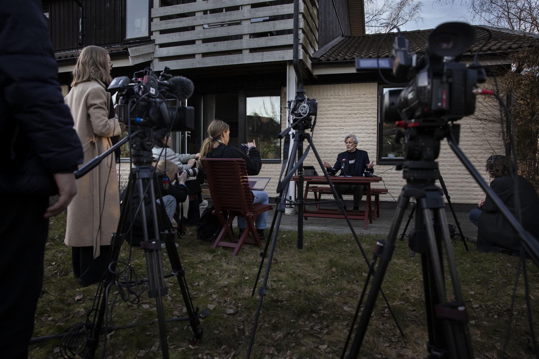 Göran Lambertz i sin trädgård framför ett uppbåd av kameror och reportrar.