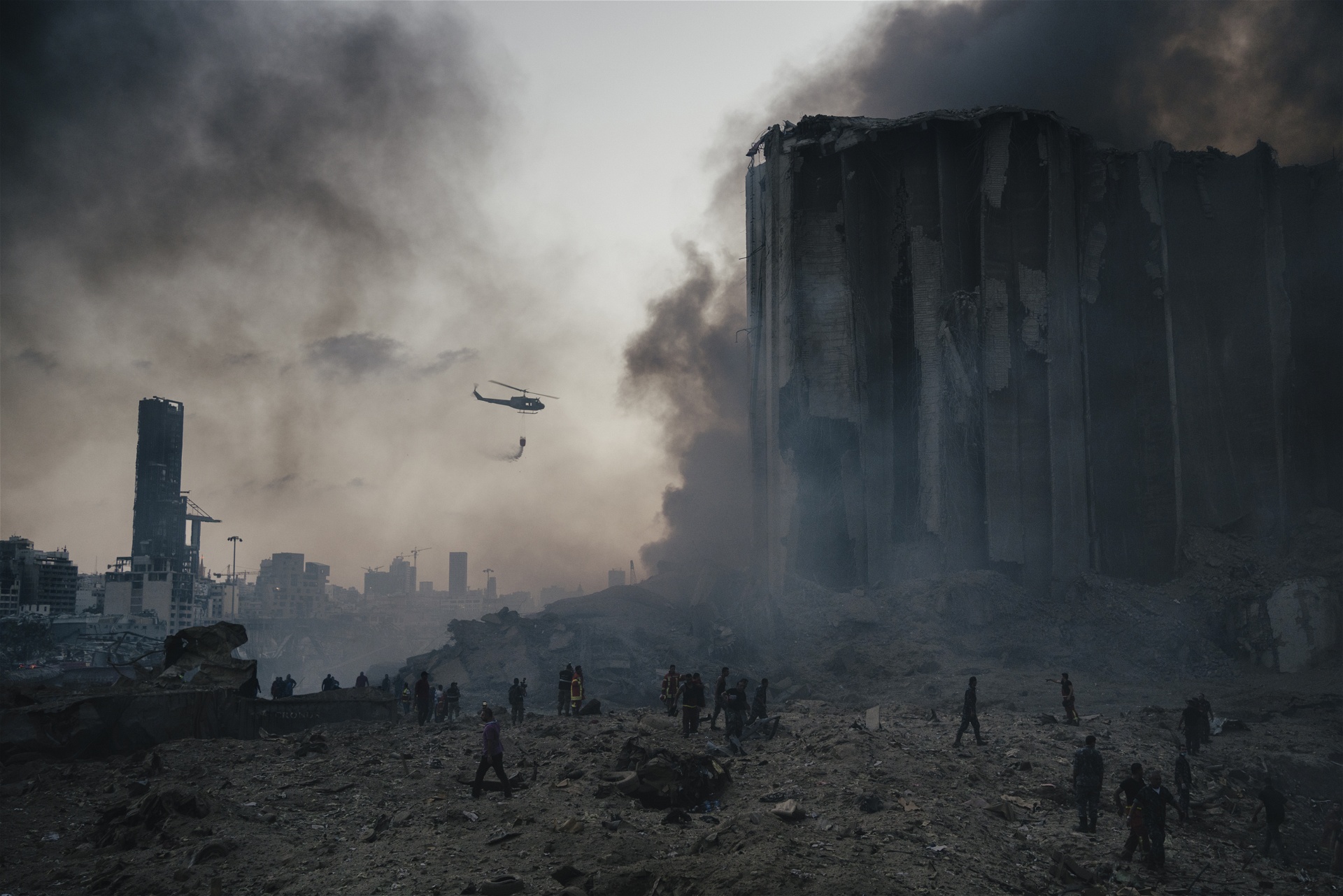 En brandsläckarhelikopter kämpar vid rasmassorna av den stora explosionen i Beiruts hamn sommaren 2020.