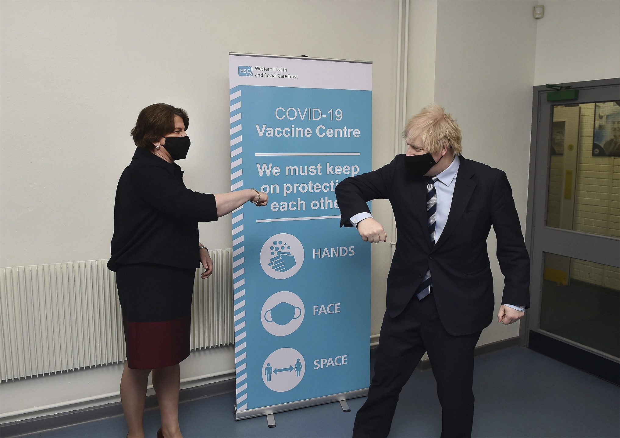 Storbritanniens premiärminsiter Boris Johnson och DUP:s partiledare Arlene Foster coronahälsar på varandra med armbågen under ett besökt på ett vaccinationscenter i Enniskillen