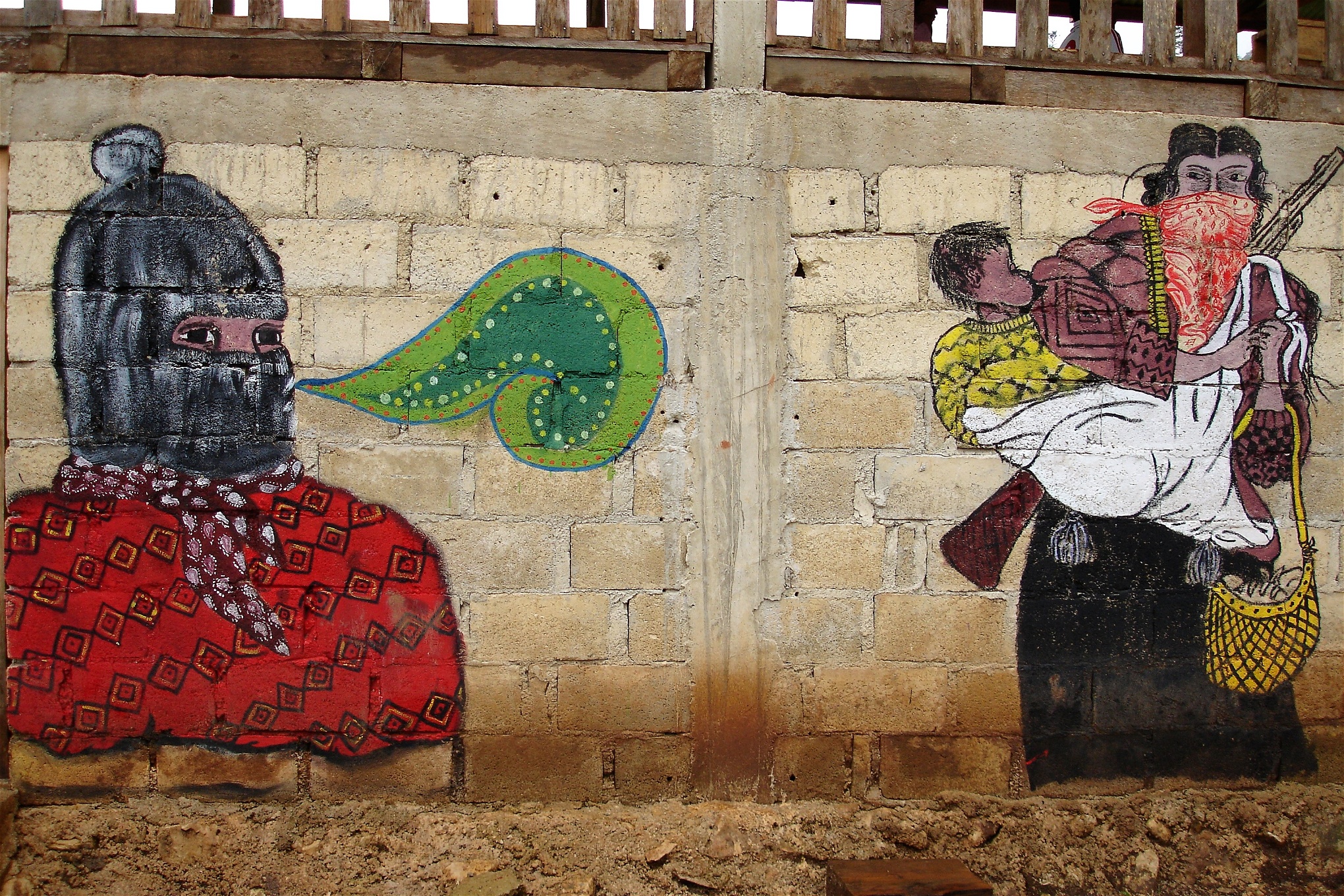 Väggmålning av en maskerad person och en kvinna med gevär och ett barn i sjal på ryggen. 