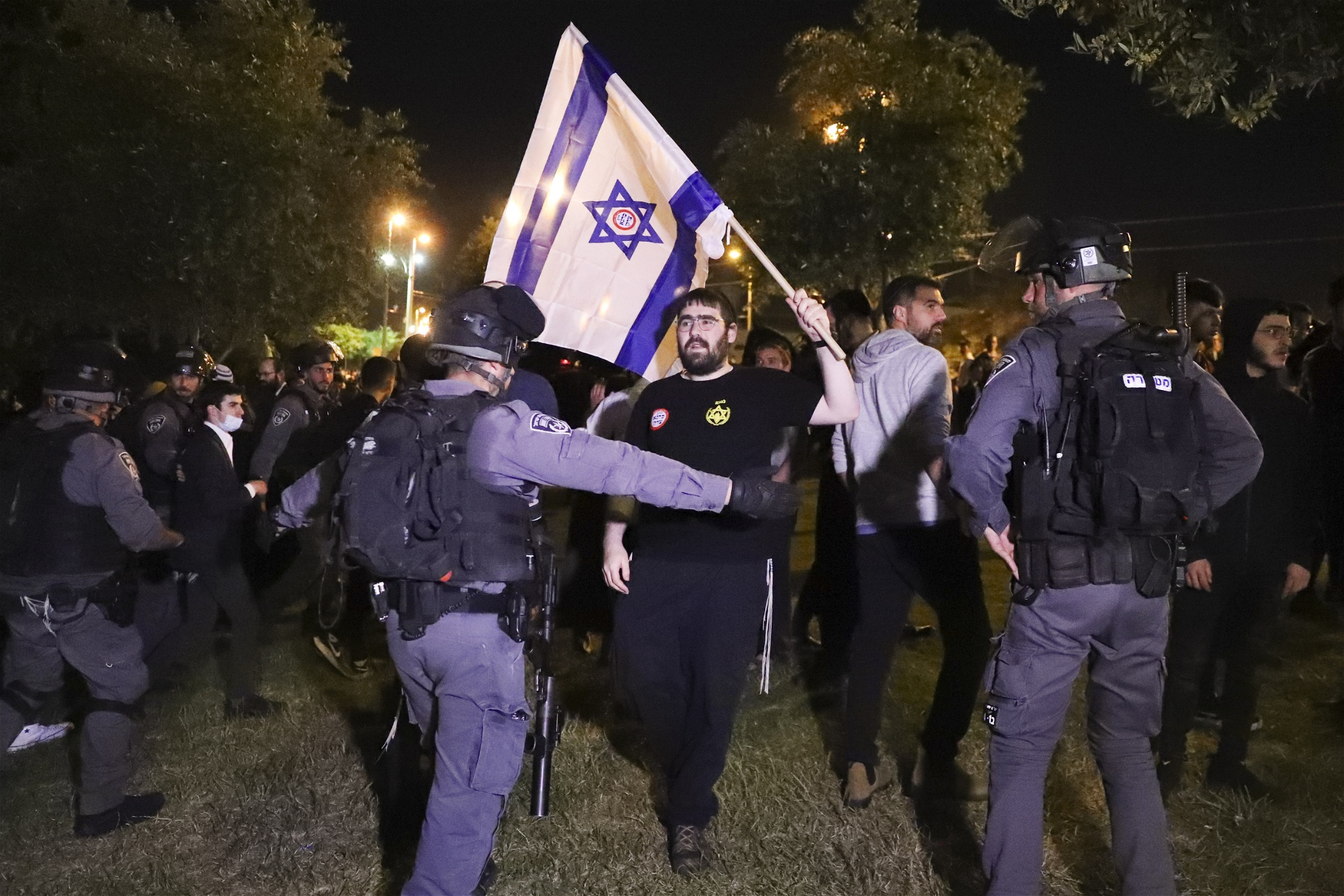 Högerextrem demonstrant i Jerusalem som viftar med israelisk flagga framför polis