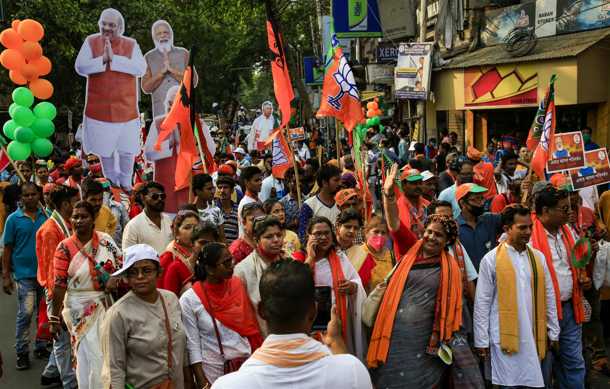 BJP-supportrar med orange sjalar, flaggor och bilder på Narendra Modi går i ett demonstrationståg.