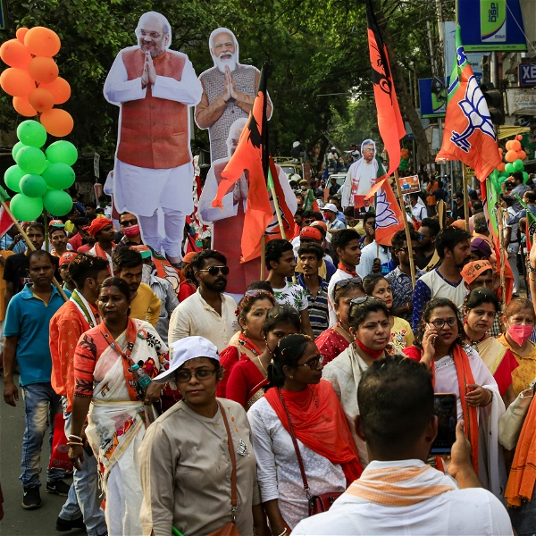 BJP-supportrar med orange sjalar, flaggor och bilder på Narendra Modi går i ett demonstrationståg.