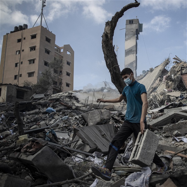 En man går genom de sönderbombade resterna av en flervåningsbyggnad.