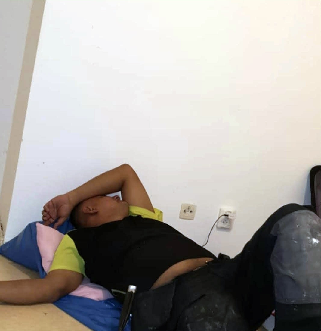 En anställd sover i sina arbetskläder direkt på golvet med bara en sovsäck som underlag