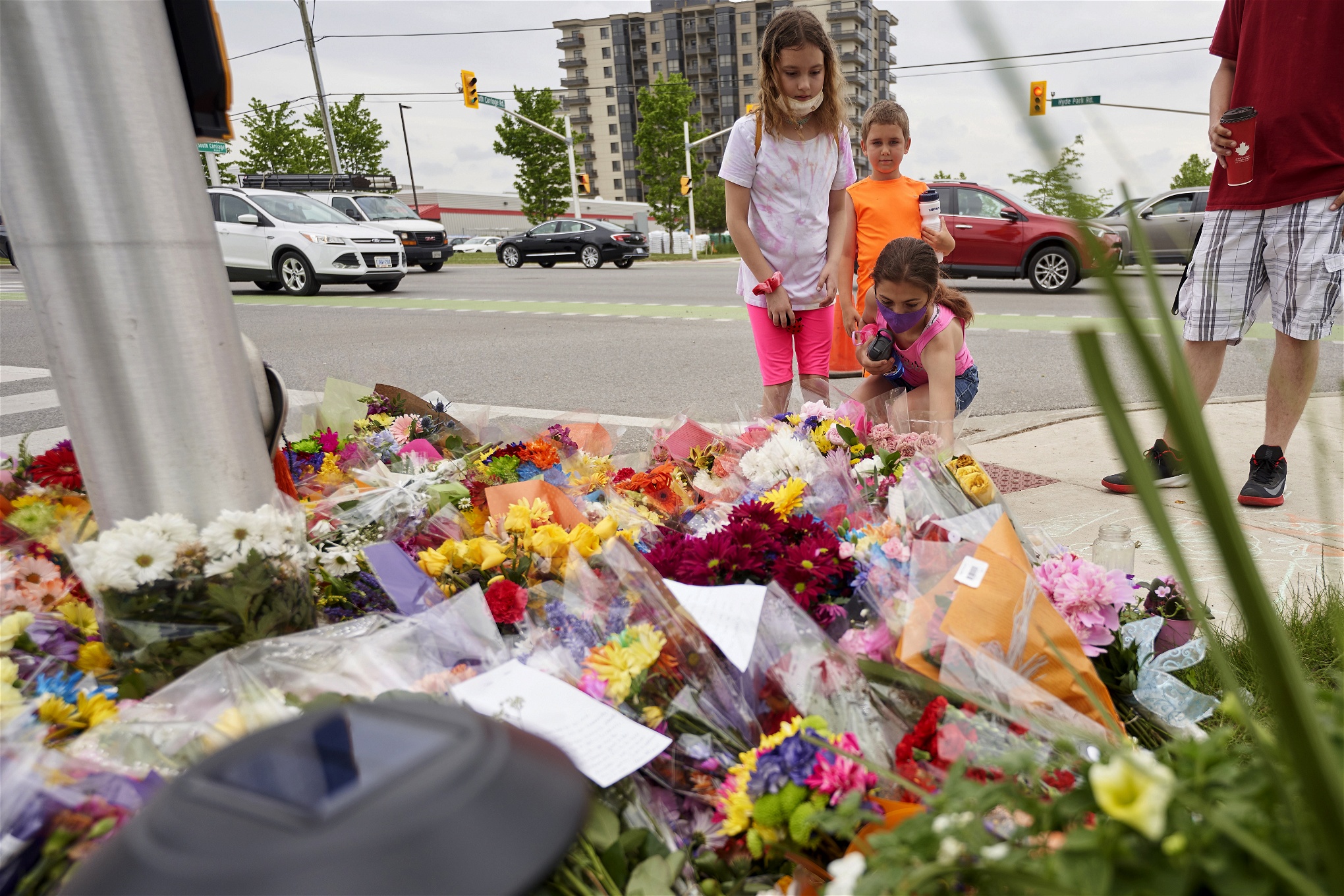 Människor lägger blommor på en trottoar i Kanada