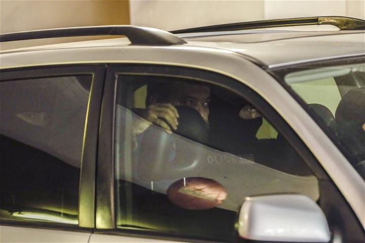 Christos Pappas, partitopp i Gyllene Gryning, sitter i en bil mellan maskerade poliser