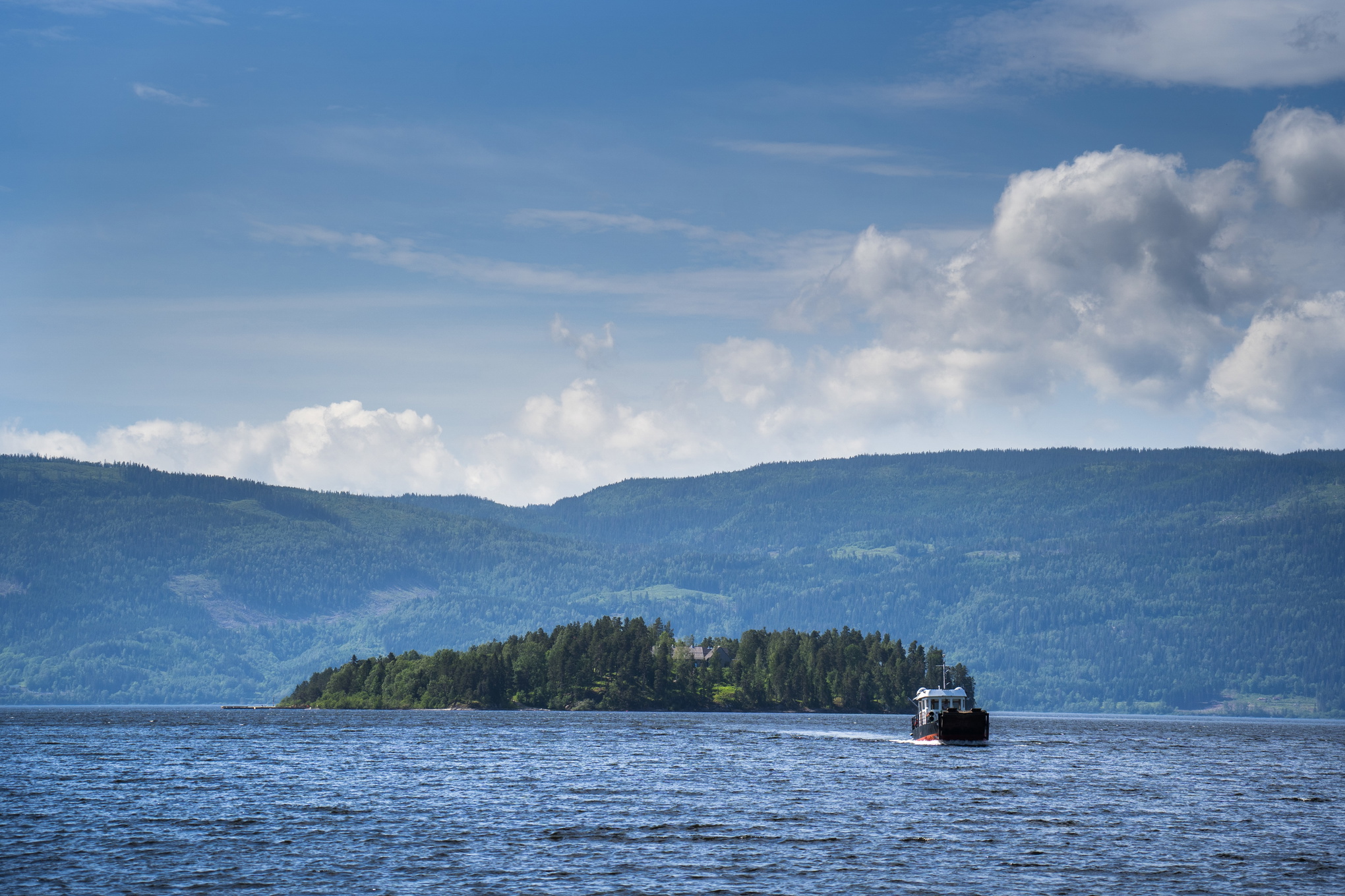 Utøya sedd på avstånd, med berg och himmel i bakgrunden.